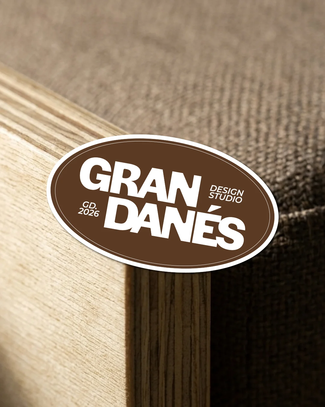 Grandanés — el sticker ovalado de la marca sobre el canto de un mueble de multilaminado y tela.
