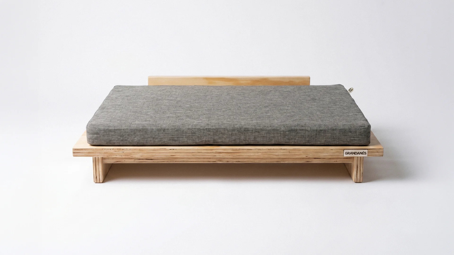 La cama Vetra, de fenólico con almohadón gris, sobre fondo blanco.